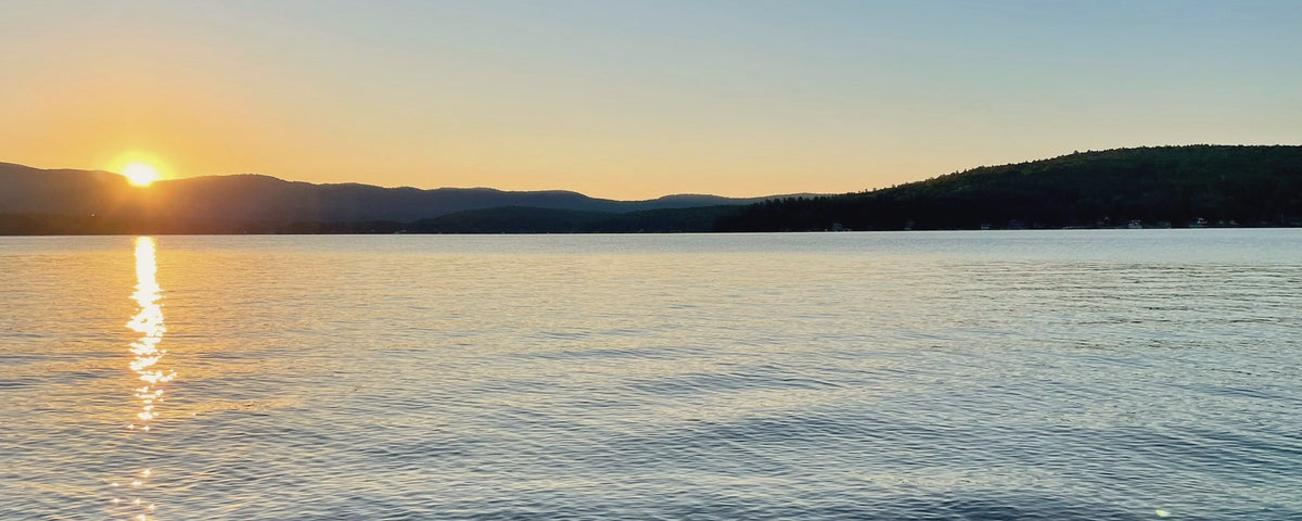 Sun setting behind hills over a calm lake at golden hour